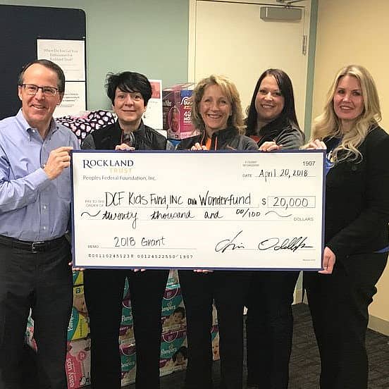 Group of 5 people holding large check made out to Wonderfund for $20,000 from Rockland Trust.