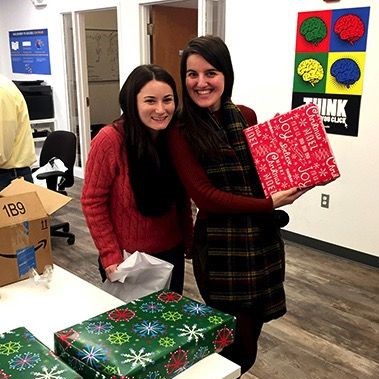 Two women smiling with wrapped gift.