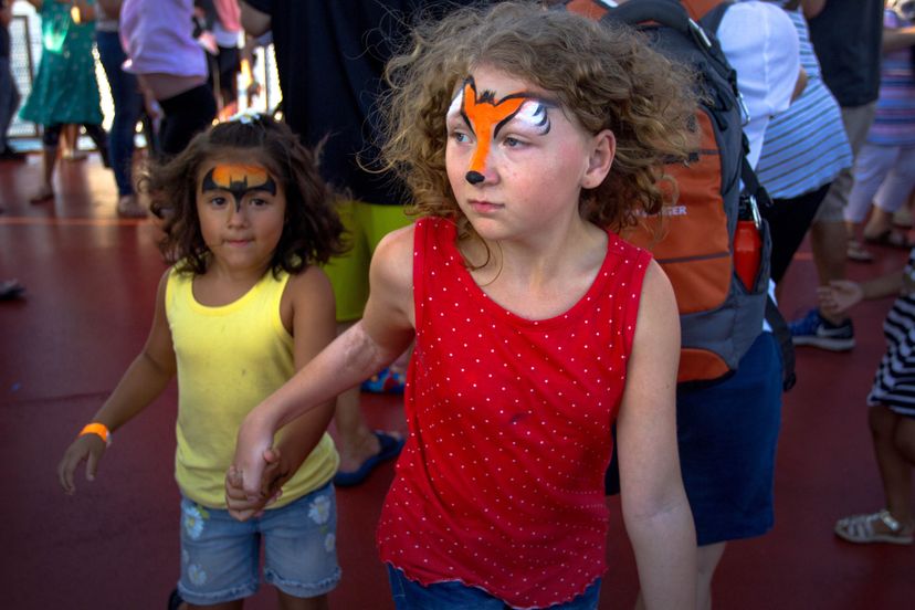 children with face paint holding hands