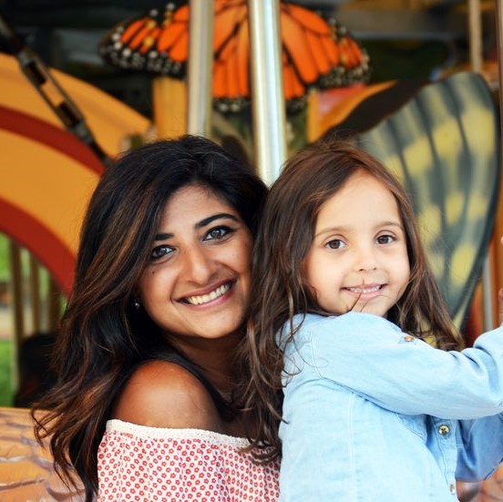 A mom and daughter smiling while on the greenway carousel